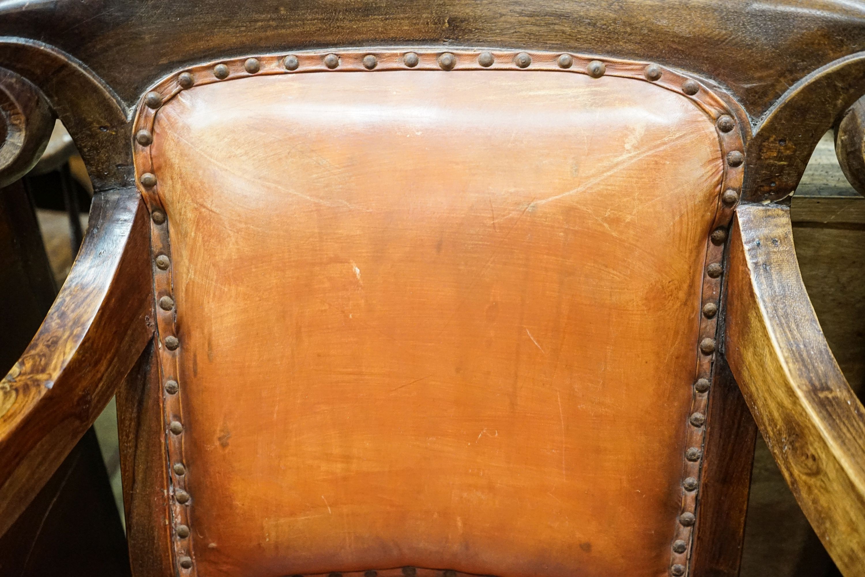 A pair of Victorian style hardwood elbow chairs with faded red leather upholstery, width 55cm, depth 45cm, height 92cm